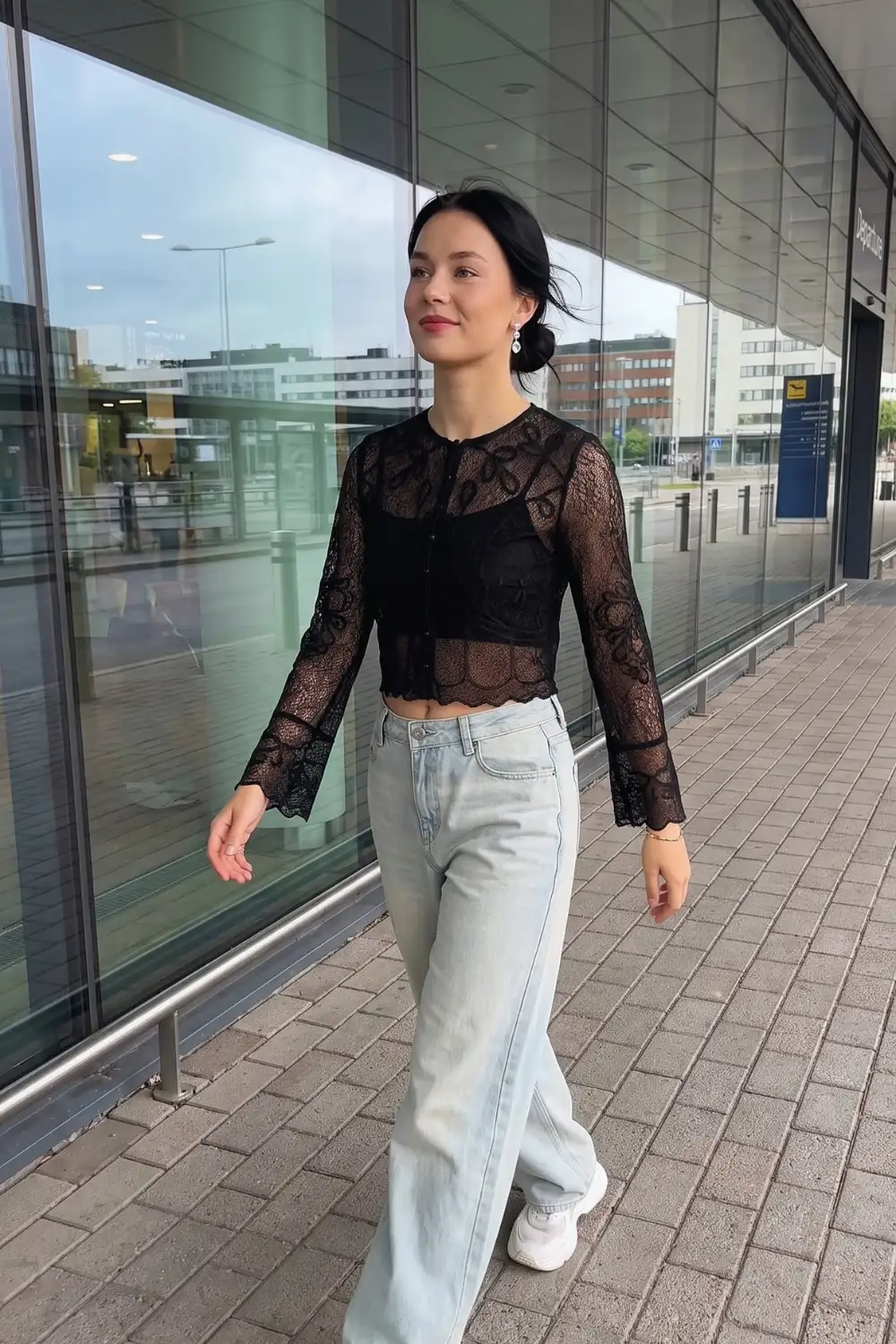 Woman in black sheer lace scallop hem crop cardigan with light wash wide leg jeans and white sneakers