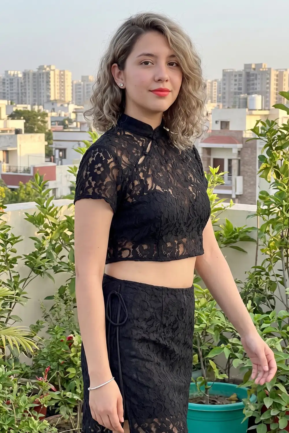 Woman in black sheer lace mandarin collar crop top with matching black lace midi skirt