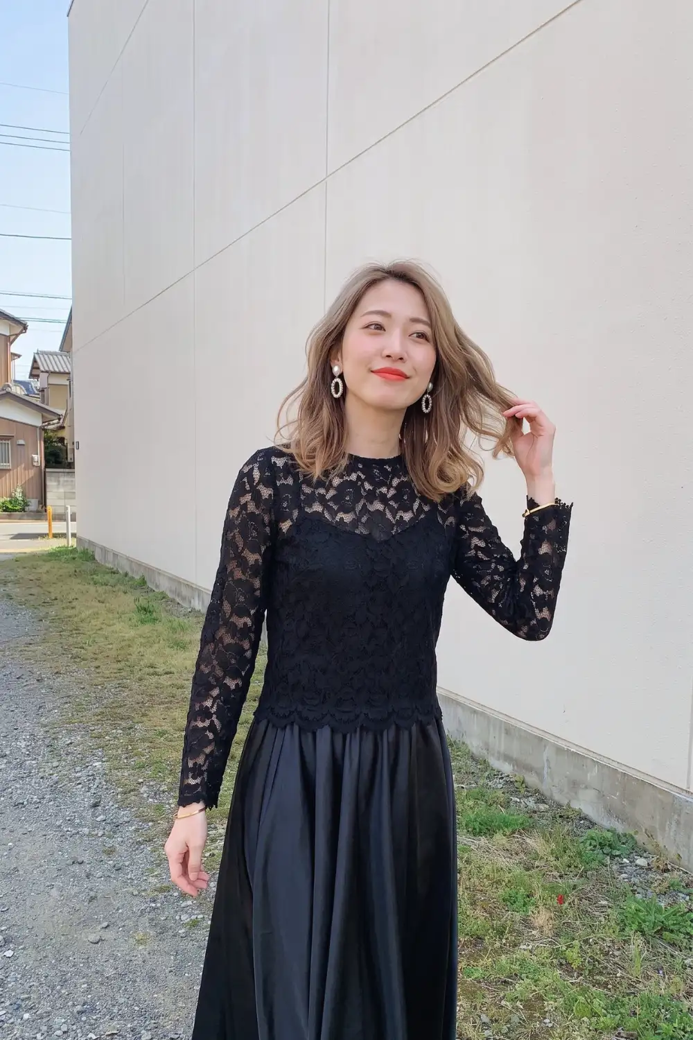 Woman in black sheer lace long sleeve fitted top with black satin midi flare skirt