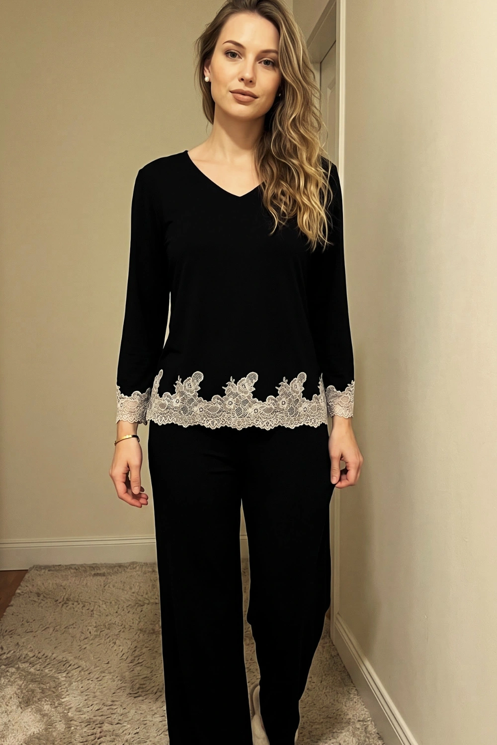 Woman in black v-neck long sleeve top with cream lace hem trim and wide leg pants loungewear set