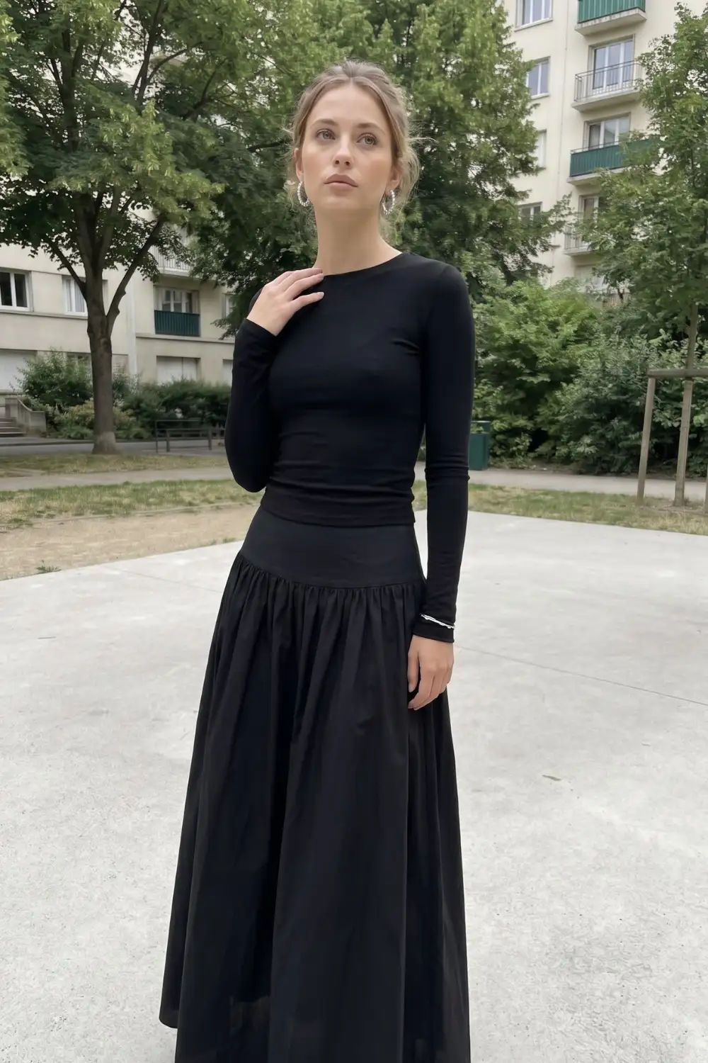 Woman in black fitted long sleeve top with black gathered drop waist maxi skirt