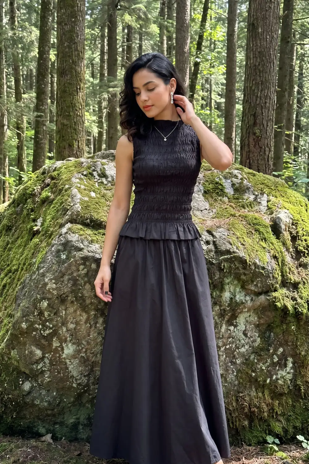 Woman in black smocked sleeveless peplum top with black cotton maxi skirt