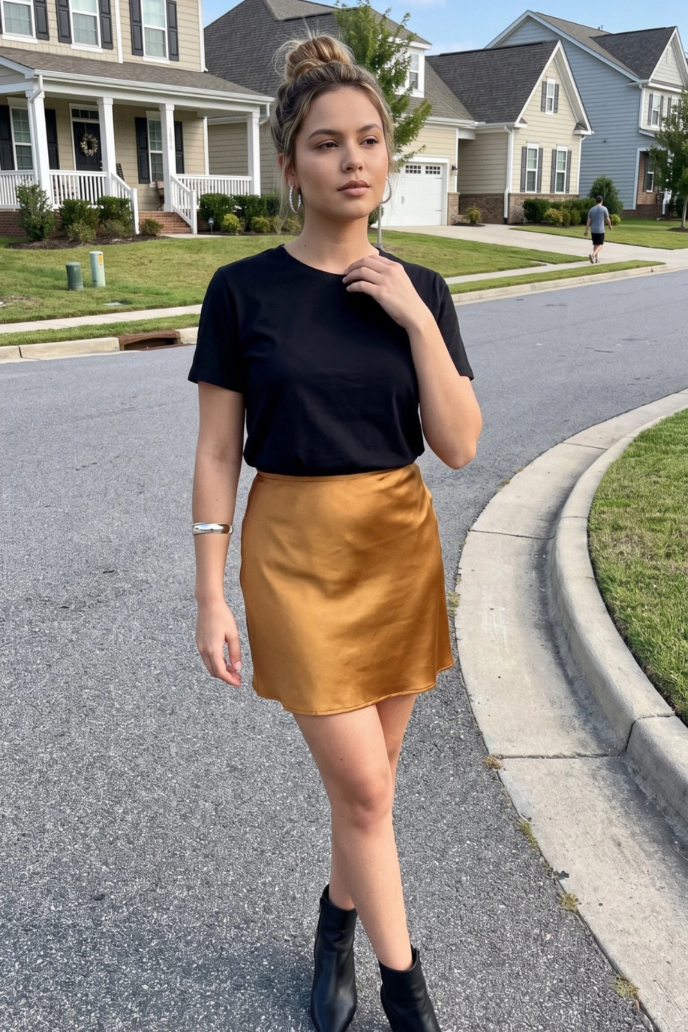 Woman in black t-shirt with mustard gold satin mini skirt and black ankle boots