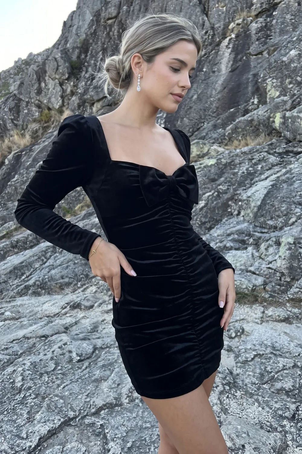 Woman in black velvet ruched sweetheart long sleeve mini dress