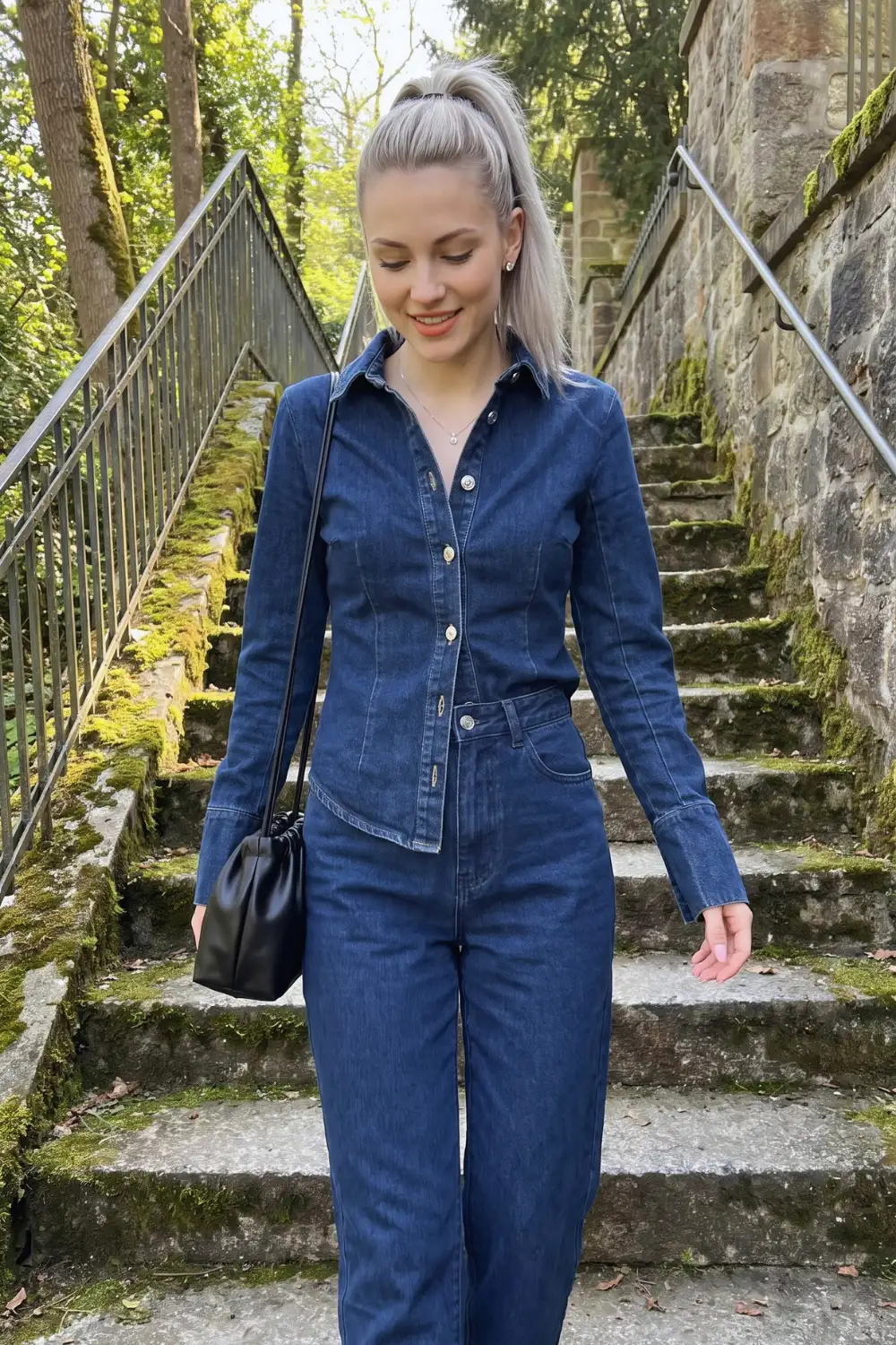 Woman in medium blue fitted denim shirt jacket with matching wide leg jeans