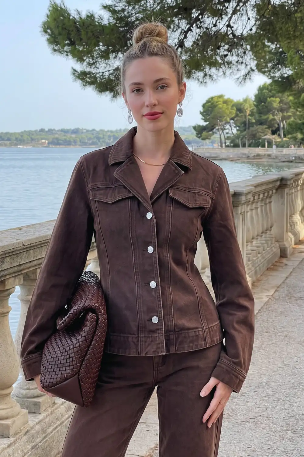 Woman in dark chocolate brown fitted denim trucker jacket with matching wide leg jeans