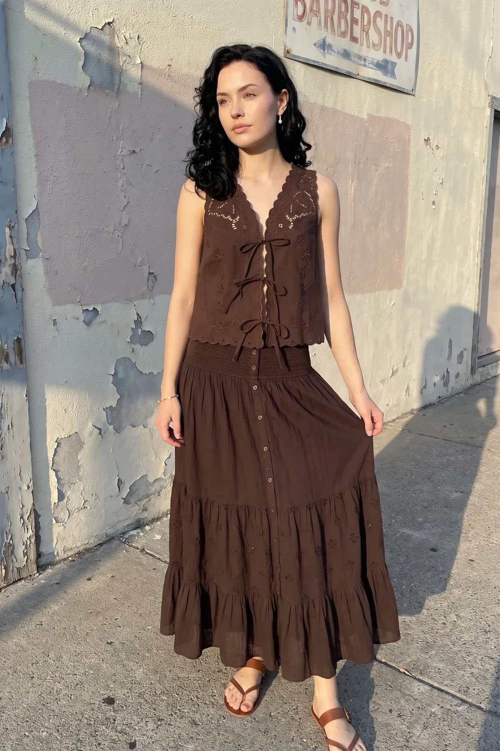 Woman in dark brown eyelet tie front sleeveless top and brown smocked waist tiered eyelet maxi skirt