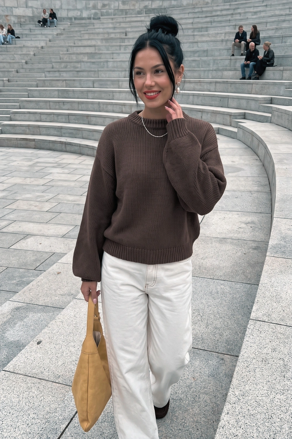 Woman in dark brown oversized mock neck knit sweater with cream wide leg jeans
