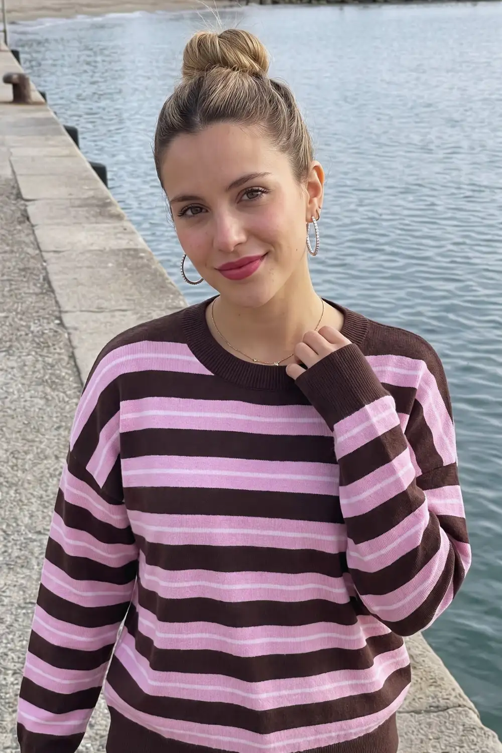 Woman in dark brown and pink striped oversized crew neck sweater