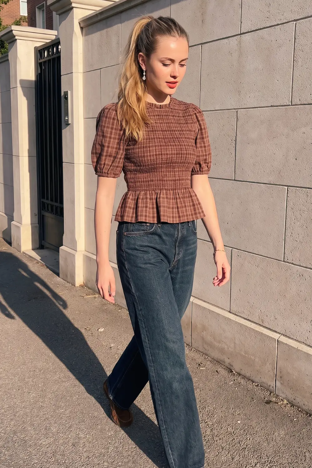 Woman in brown plaid smocked puff sleeve peplum top and dark blue wide leg jeans