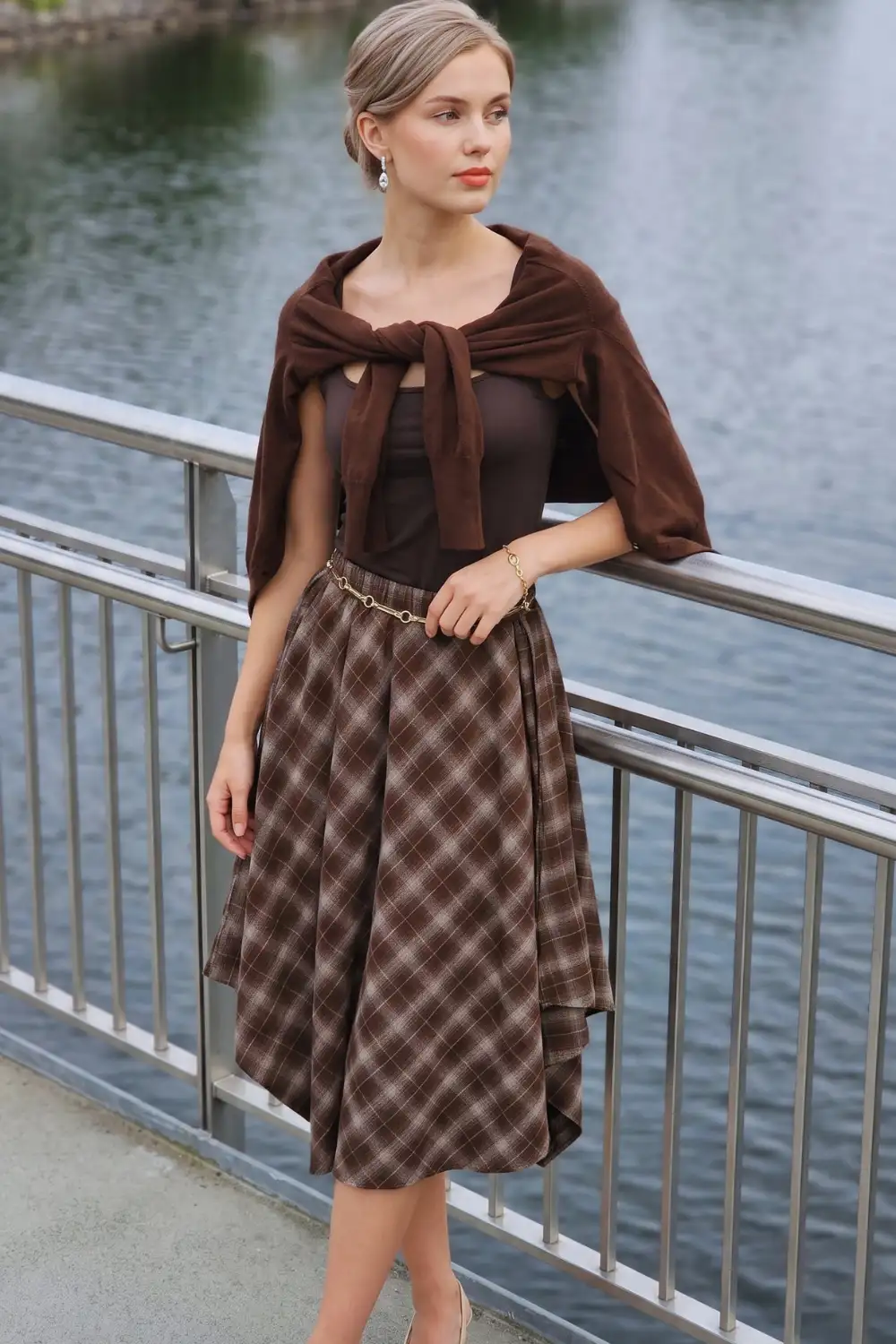 Woman in dark brown ribbed polo sweater with brown plaid mini skirt and knee high boots