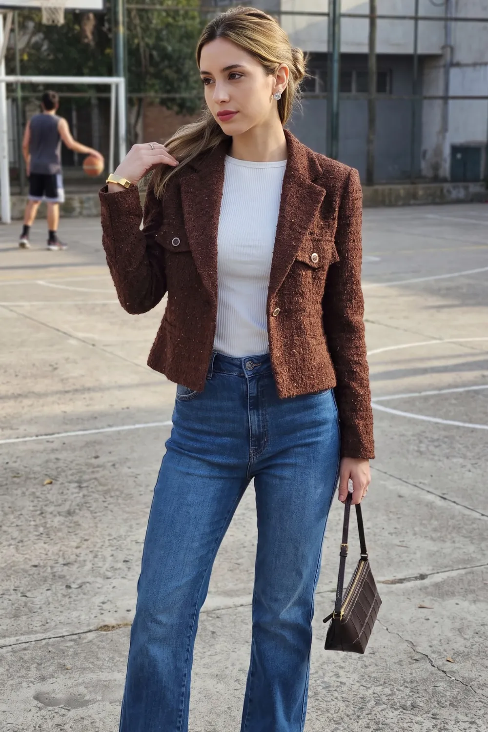 Woman in brown tweed cropped blazer with white ribbed top and blue straight jeans