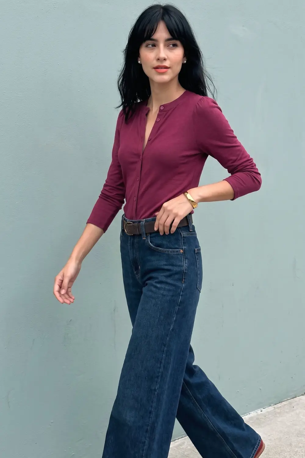 Woman in burgundy three quarter sleeve henley button top and dark blue wide leg jeans