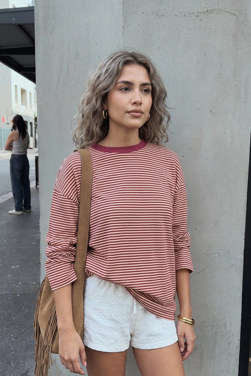 Woman in burgundy white striped oversized long sleeve top with white lace shorts