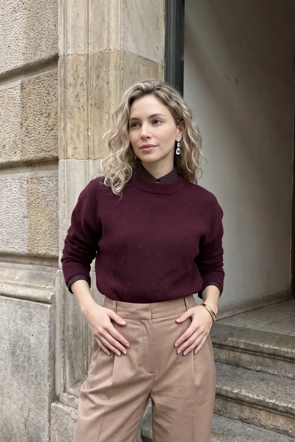Woman in burgundy crew neck sweater over dark shirt with taupe wide leg trousers