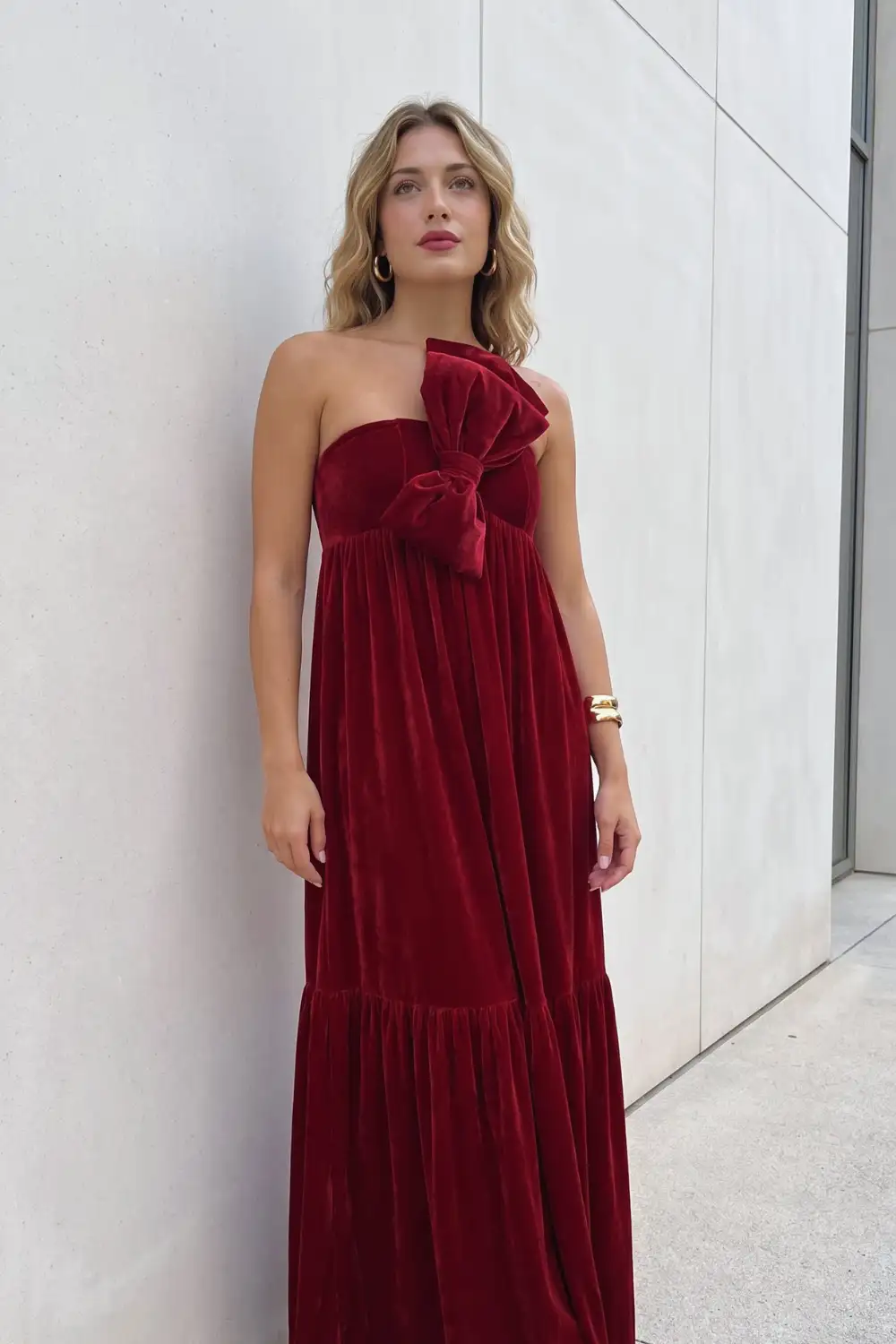 Woman in burgundy velvet strapless oversized bow tiered maxi dress