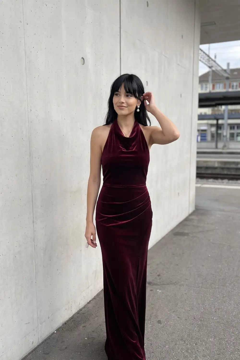 Woman in burgundy velvet cowl halter neck ruched fitted maxi dress