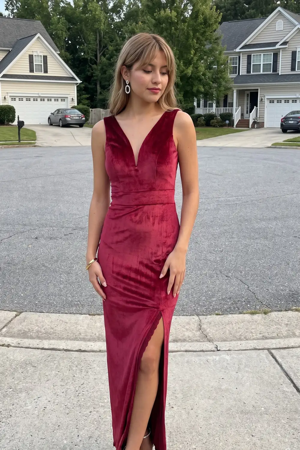 Woman in burgundy red velvet deep v-neck sleeveless fitted maxi dress with side slit