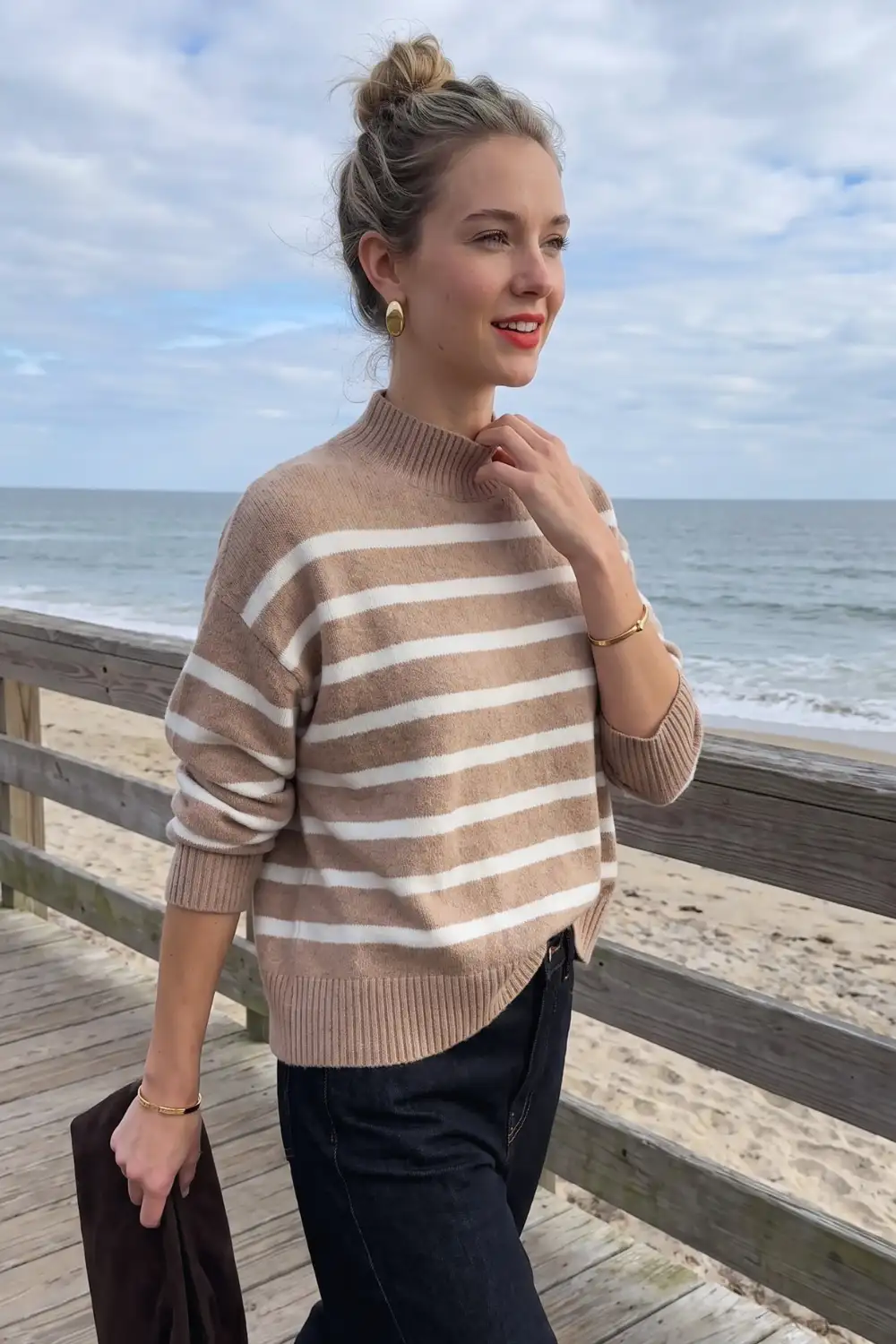 Woman in camel and white striped oversized sweater with dark navy wide leg jeans
