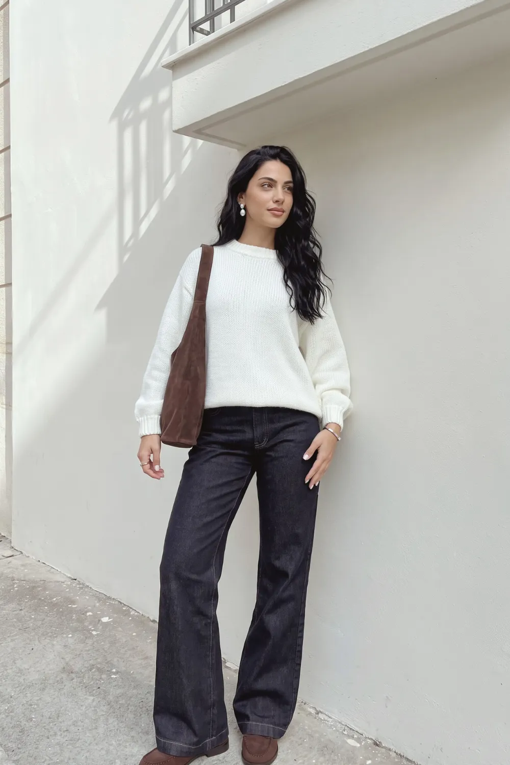 Woman in cream oversized knit sweater with dark navy wide leg jeans and brown cowboy boots