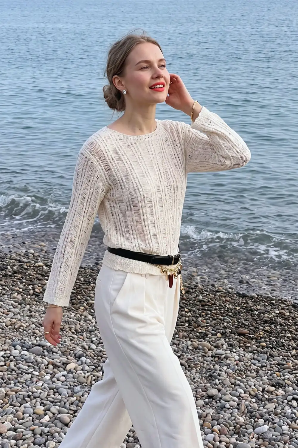 Woman in cream pointelle knit sweater with white wide leg trousers and black belt