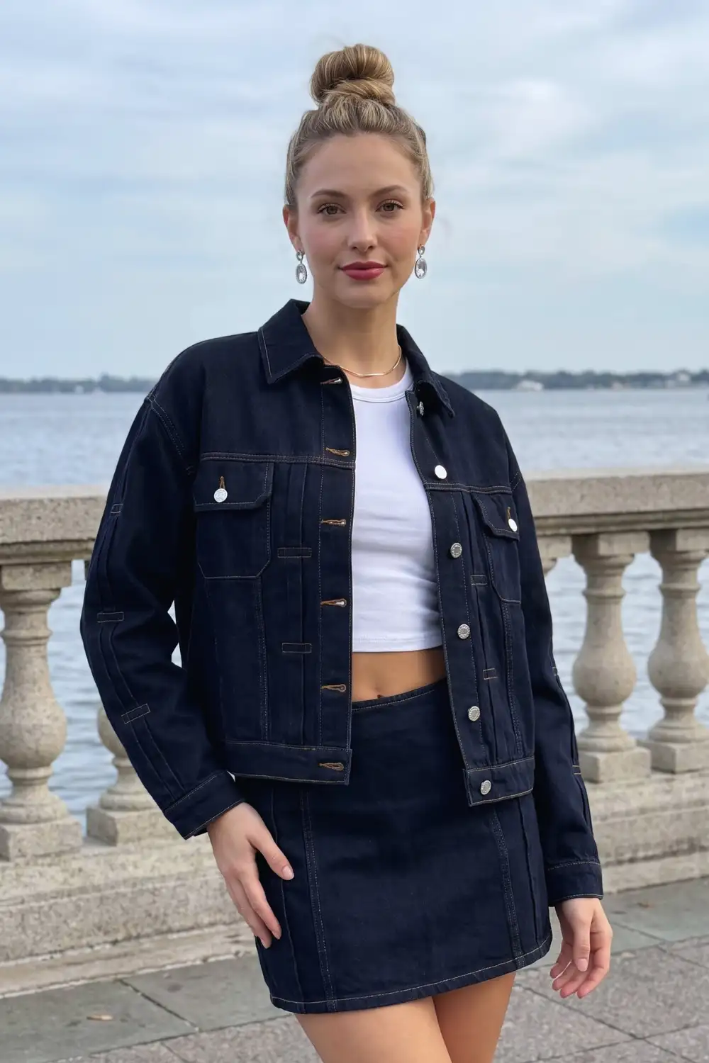 Woman in dark navy oversized denim jacket with white crop top and matching denim mini skirt