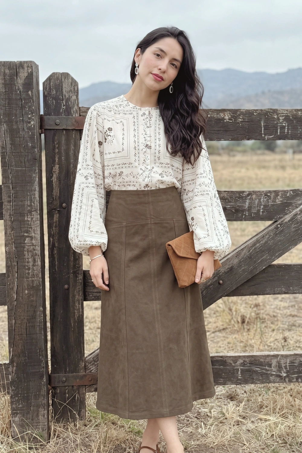 Woman in cream brown floral print balloon sleeve blouse and olive suede a-line midi skirt