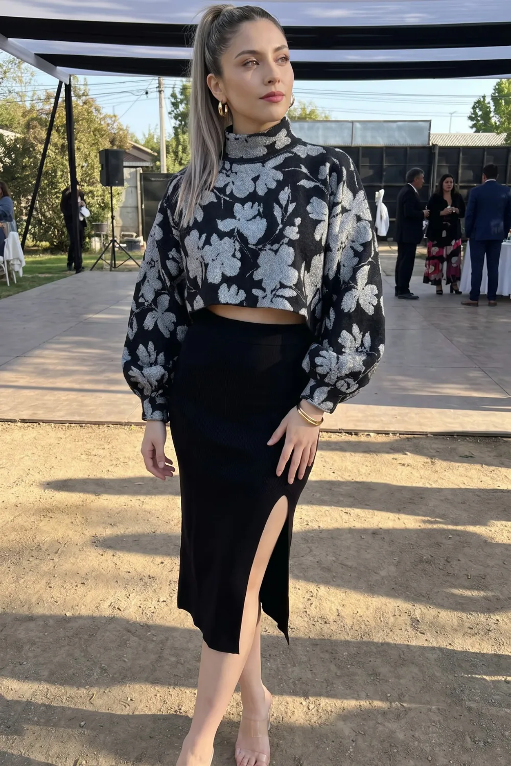 Woman in black and white floral cropped knit sweater with black midi slit skirt
