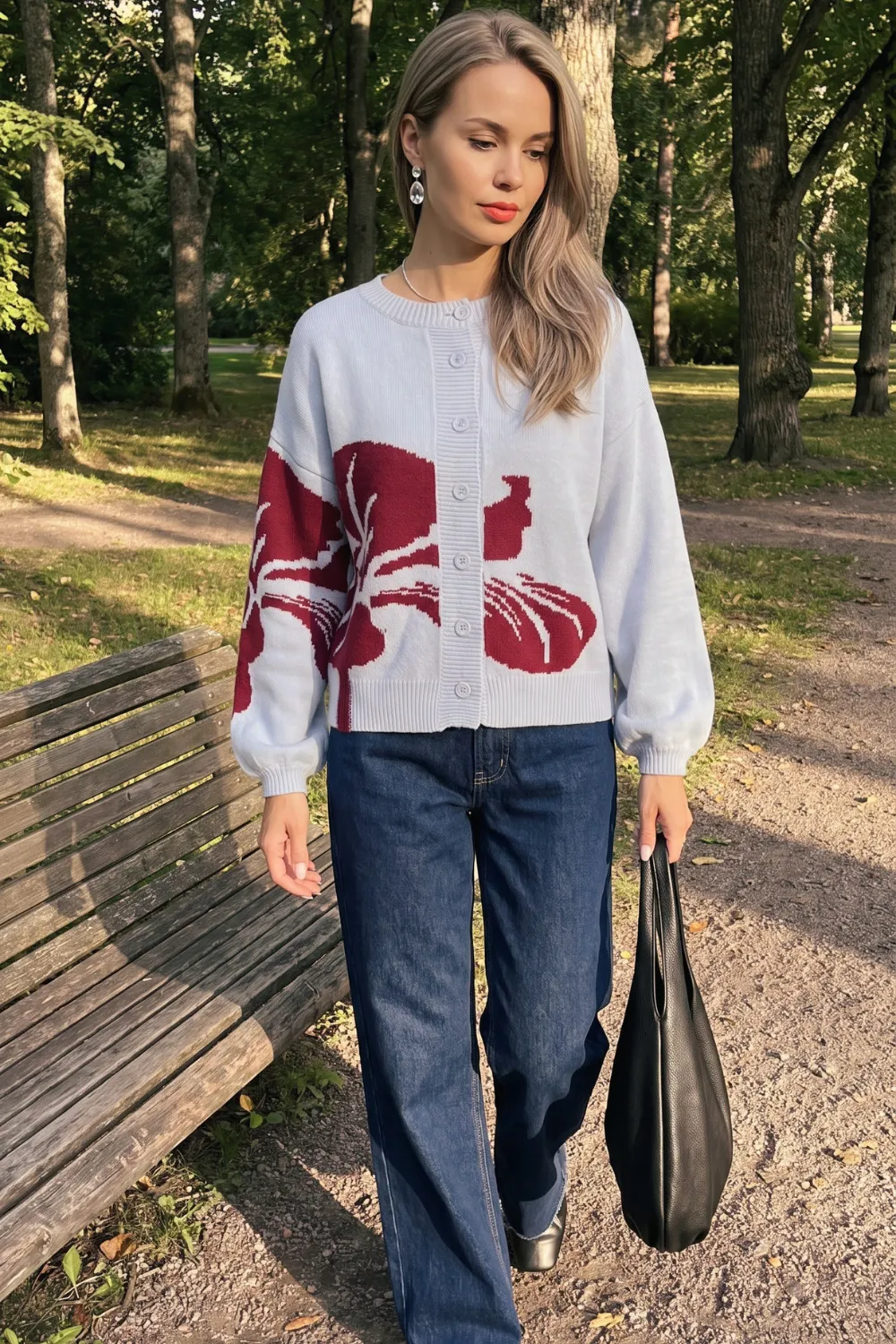 Woman in white and burgundy floral knit cardigan with dark blue wide leg jeans