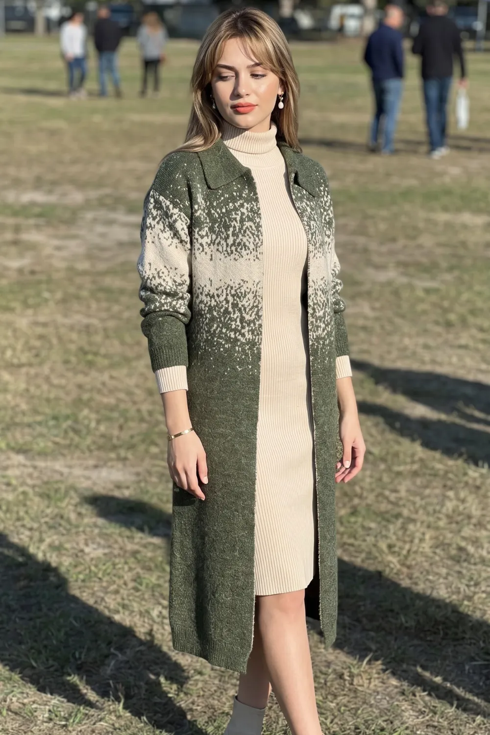 Woman in green and cream patterned longline knit cardigan over cream ribbed turtleneck midi dress