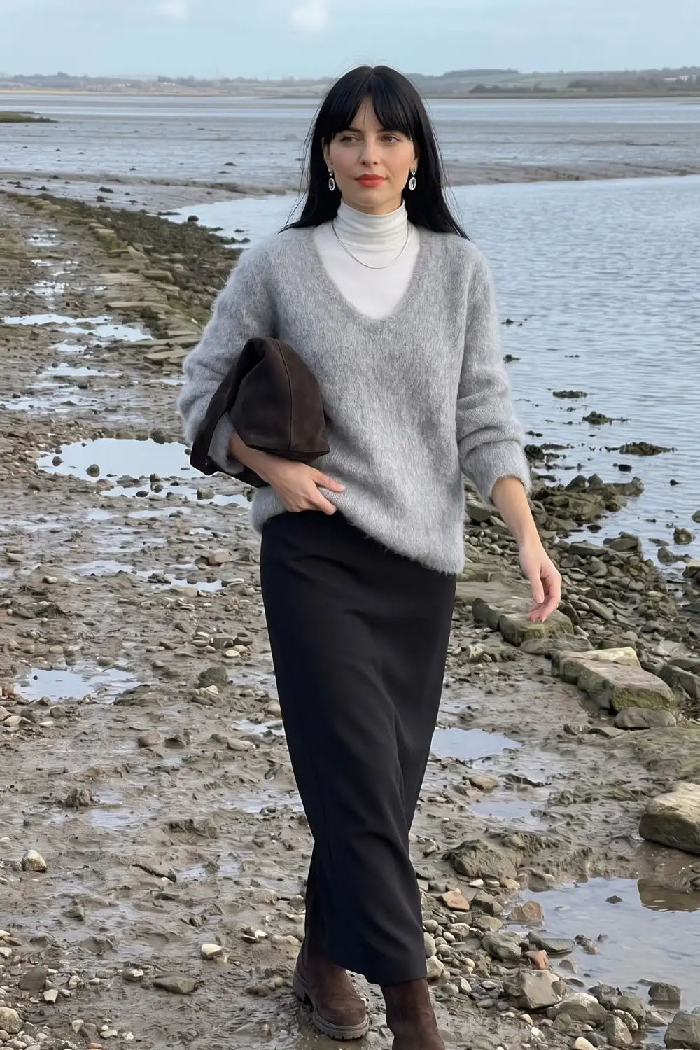 Woman in grey oversized fluffy sweater over white turtleneck with black fitted maxi skirt and dark brown boots