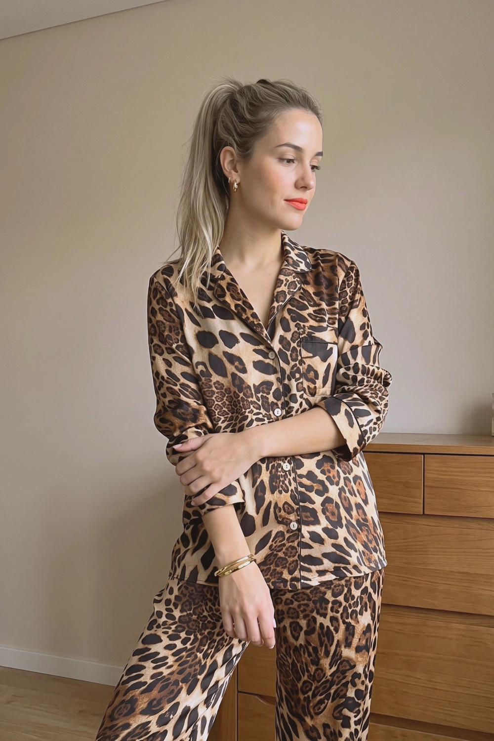 Woman in tan brown black leopard print satin long sleeve button down shirt and wide leg pants pajama set