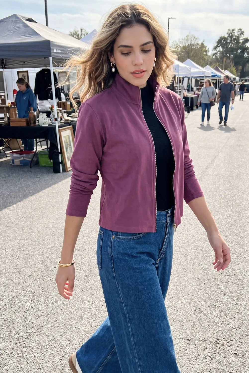 Woman in mauve purple zip mock neck jacket with black turtleneck and blue wide leg jeans
