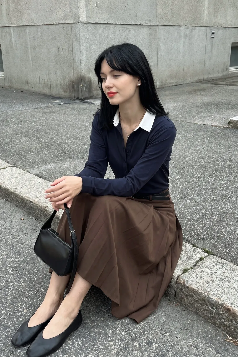 Woman in navy blue white collar button cardigan and brown pleated midi skirt with black ballet flats