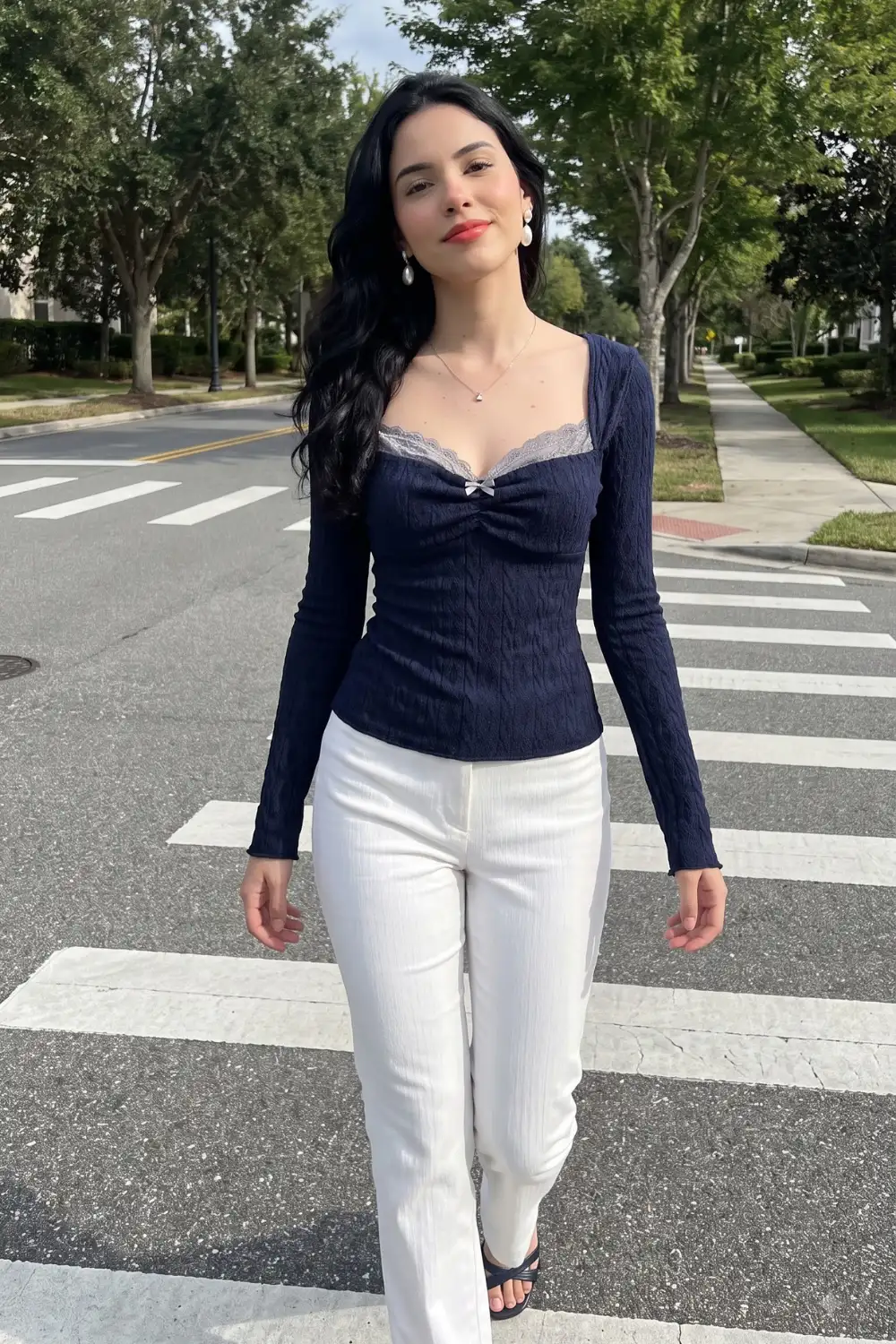 Woman in navy cable knit lace trim sweetheart neck top with white straight leg trousers