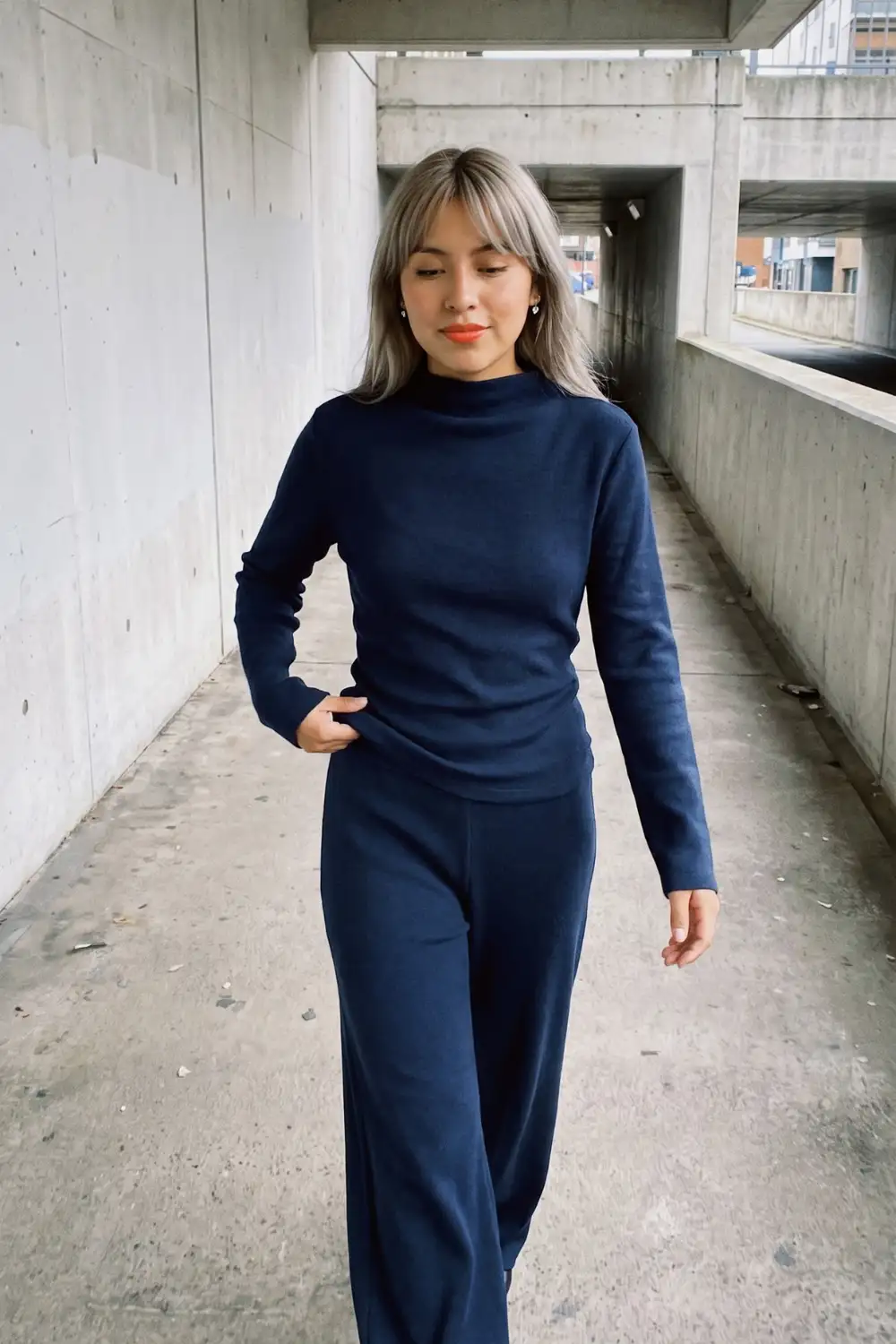 Woman in navy blue mock neck sweater and matching wide leg knit trousers
