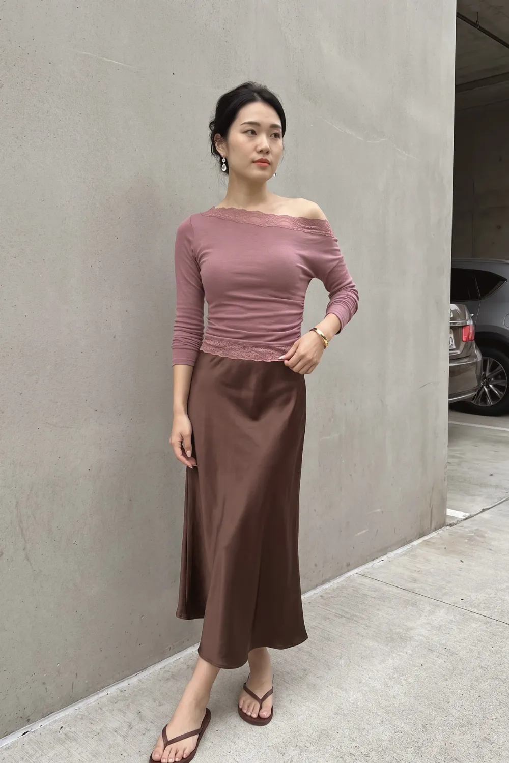 Woman in dusty pink lace trim off shoulder long sleeve top and chocolate brown satin midi skirt