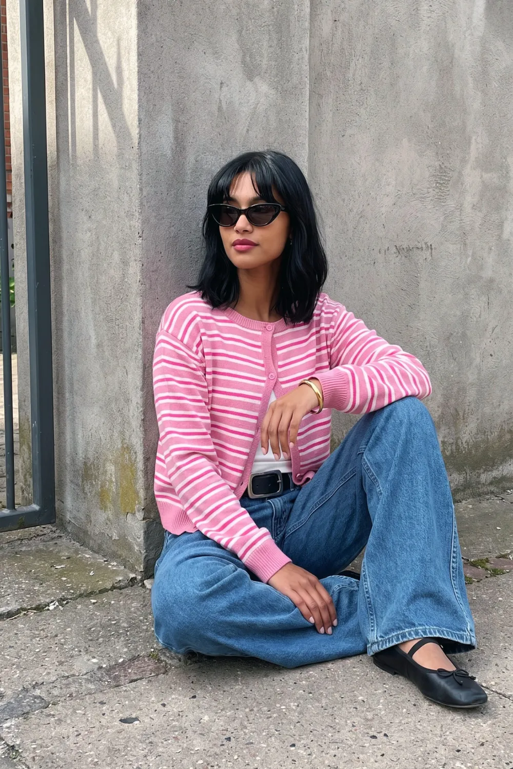 Woman in pink striped knit cardigan with blue wide leg jeans and black belt