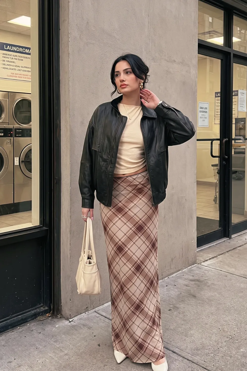 Woman in cream ribbed top beige brown plaid satin maxi skirt and black leather bomber jacket