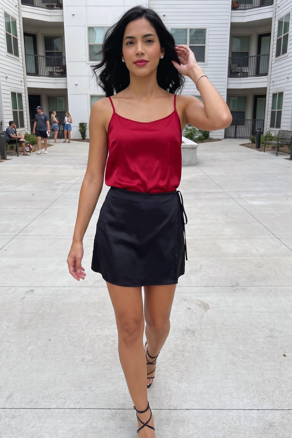 Woman in crimson red satin cami top with black satin wrap mini skirt
