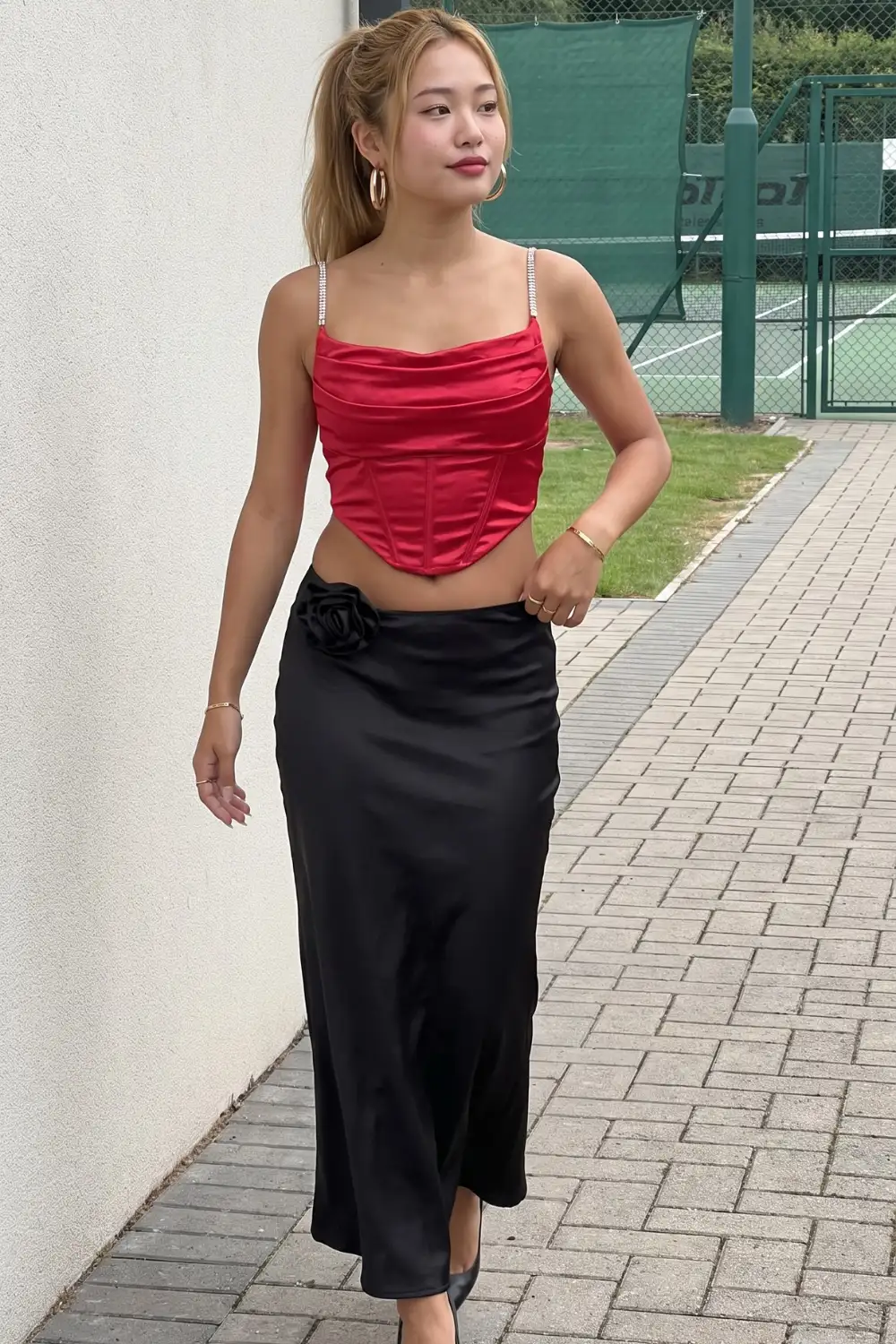 Woman in red satin cowl neck corset crop top with black satin maxi skirt and black heels
