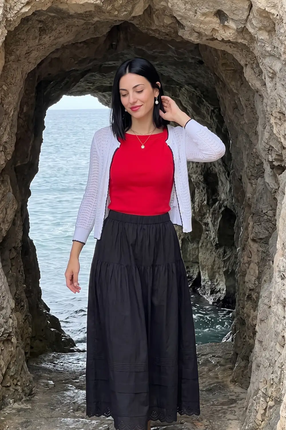 Woman in red sleeveless top with white knit cardigan and black tiered eyelet maxi skirt