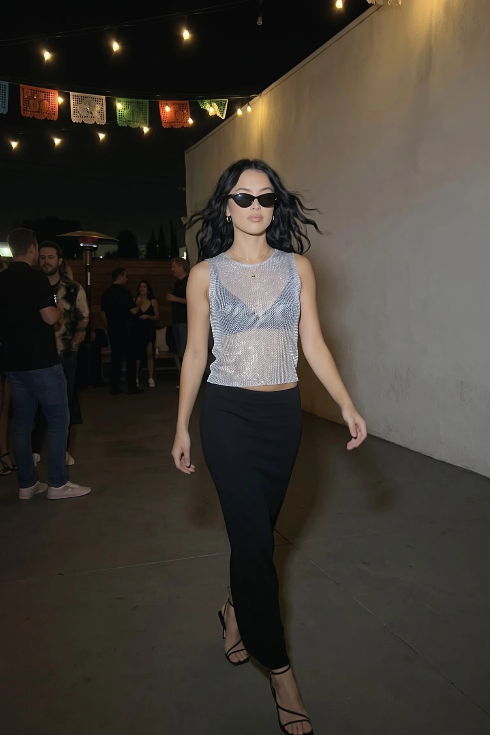 Woman in silver sequin sheer mesh crop top and black fitted maxi skirt