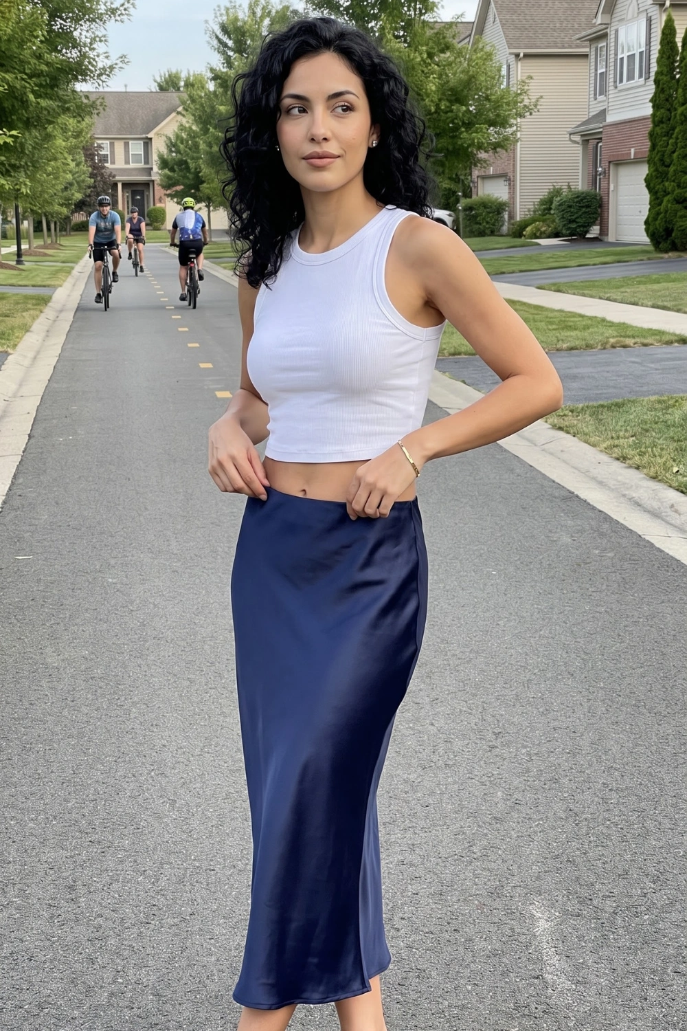 Woman in white ribbed crop tank top with navy blue satin bias cut midi skirt