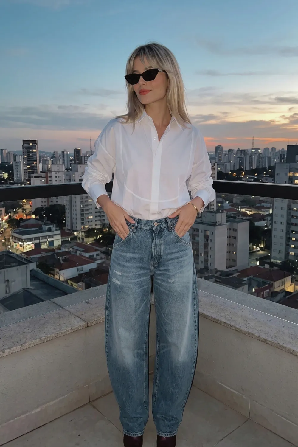 Woman in white oversized shirt with light wash distressed barrel jeans and burgundy boots