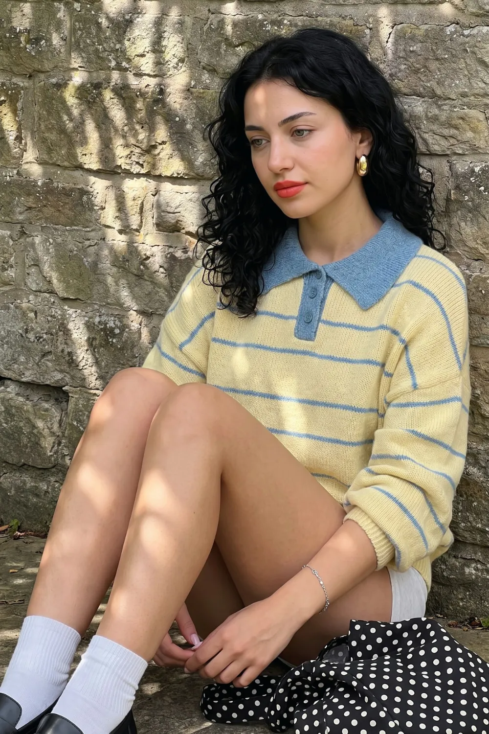 Woman in yellow blue striped polo knit sweater with black white polka dot mini skirt