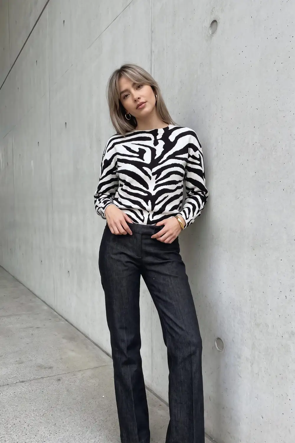 Woman in black and white zebra print sweater with dark wide leg jeans
